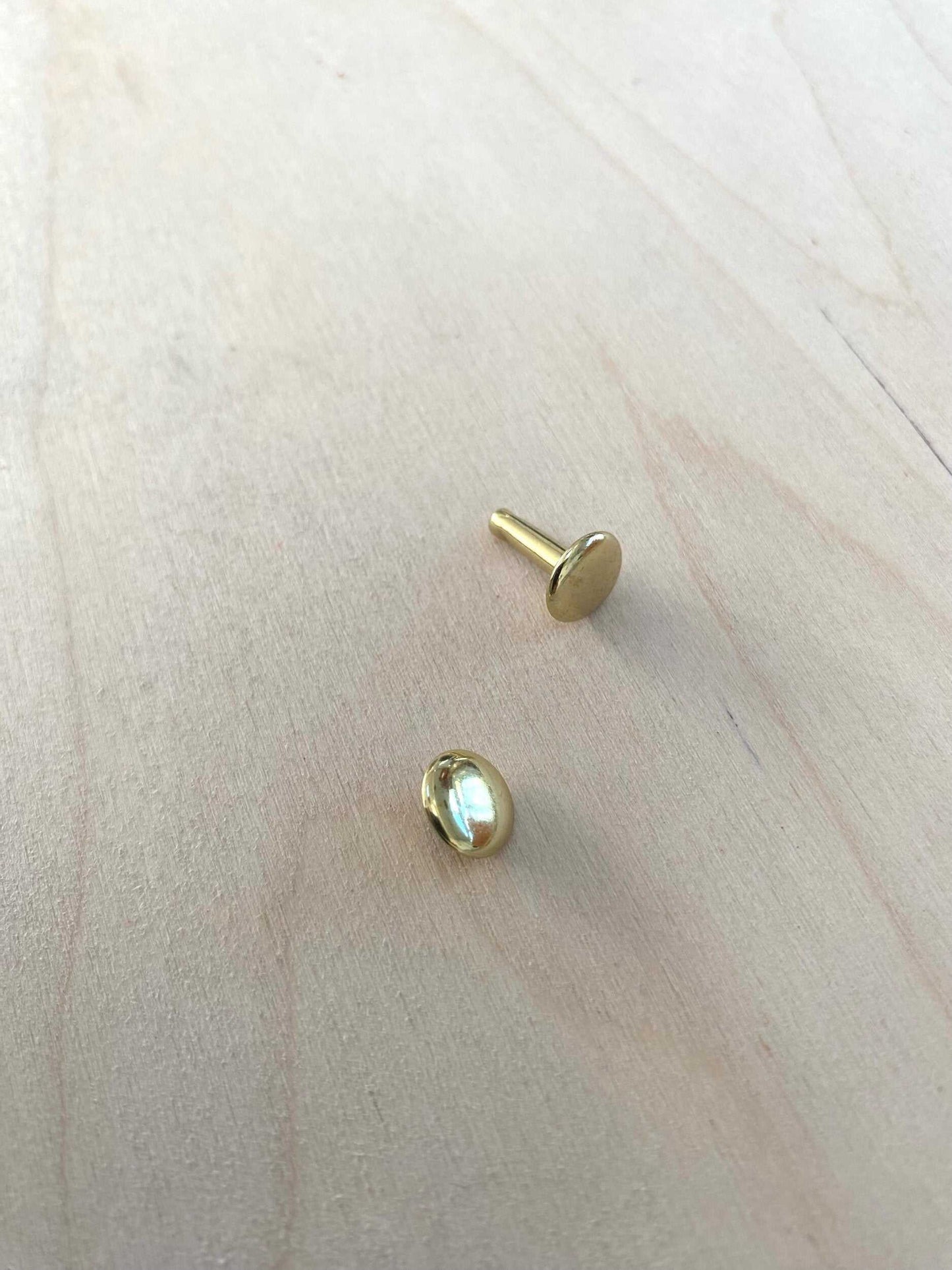 Solid Brass Double Cap Rivets on wooden surface, showcasing durable and stylish design for crafting projects.