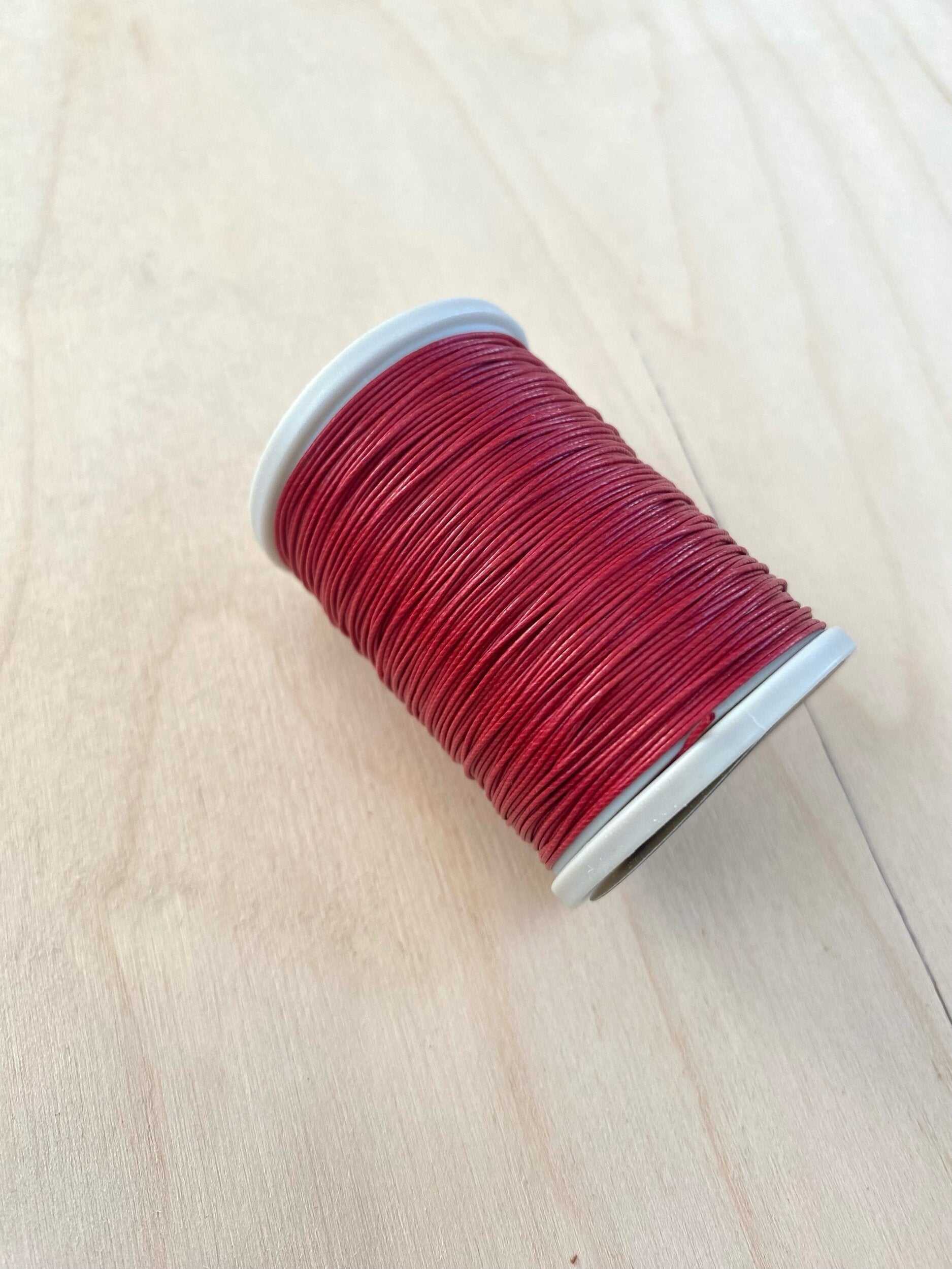 Red Cotton Linen Thread 0.55 mm spool on wooden surface.