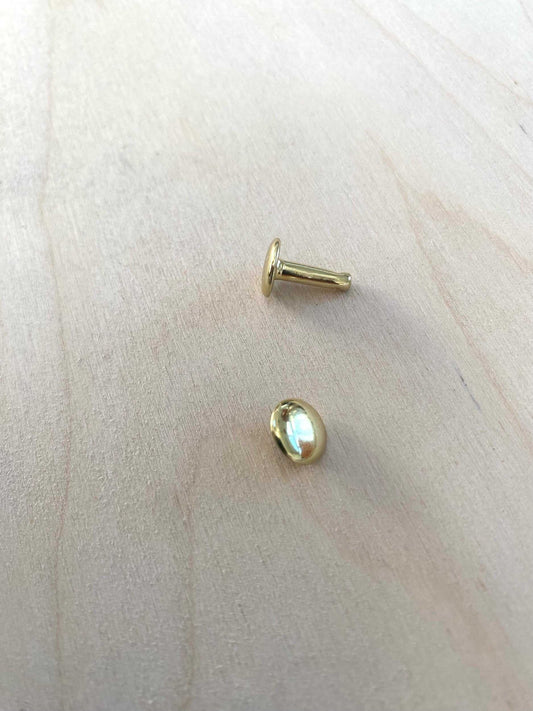 Solid Brass Double Cap Rivet on wooden surface, showcasing durability and elegance.