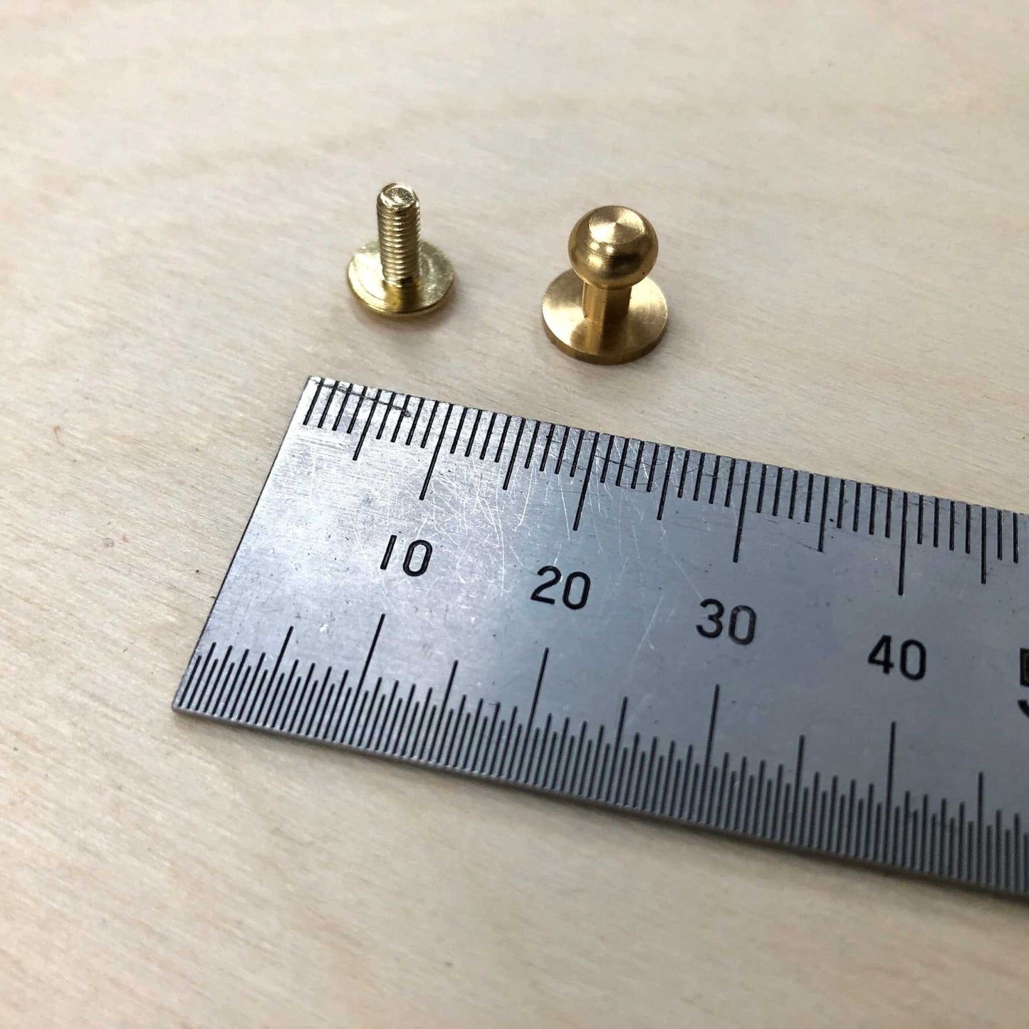 Sam Browne Studs solid brass embellishments with screws next to a ruler for size reference.