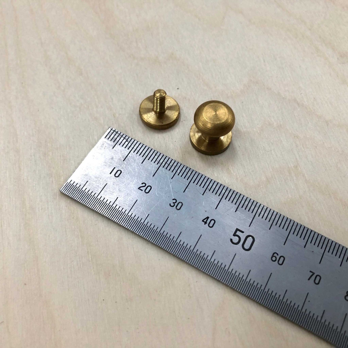 Sam Browne Studs in solid brass with screws for leather embellishment next to a ruler for size reference.