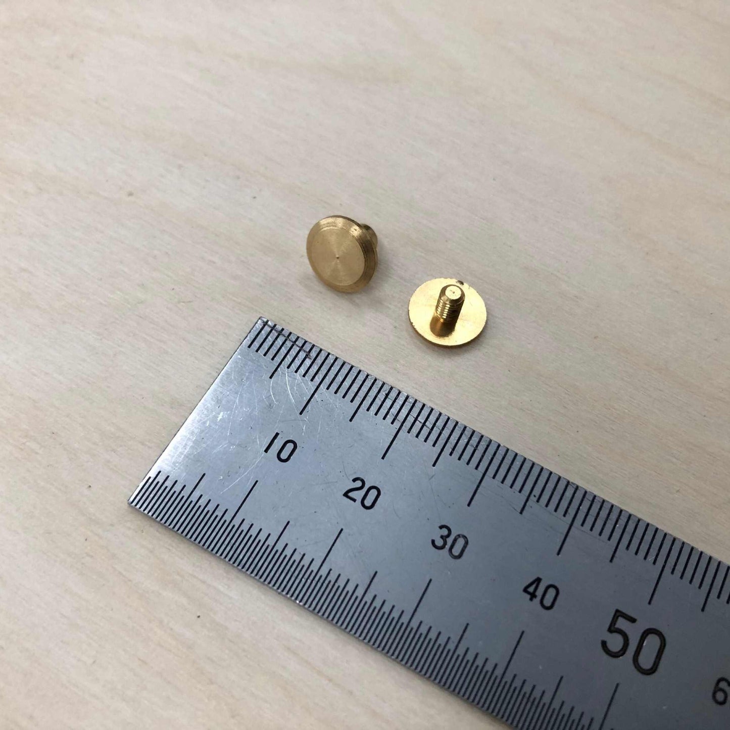 Chicago Screws in solid brass next to a ruler for size reference.