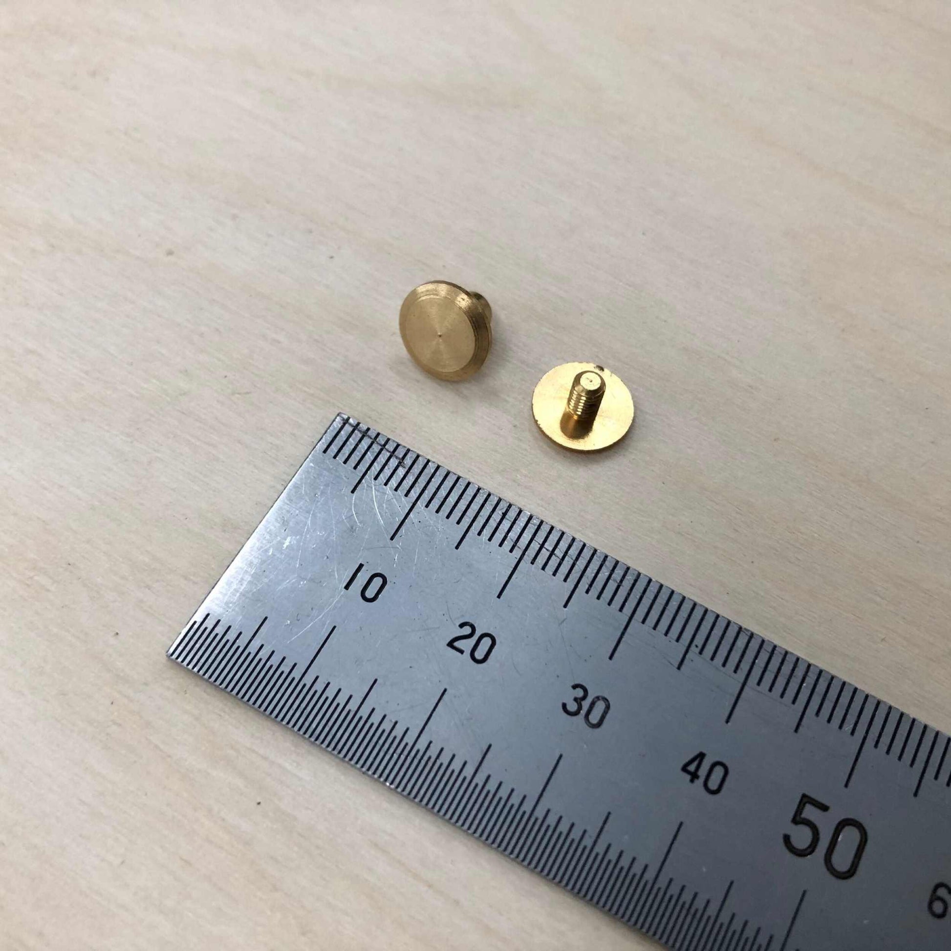 Chicago Screws in solid brass next to a ruler for size reference.