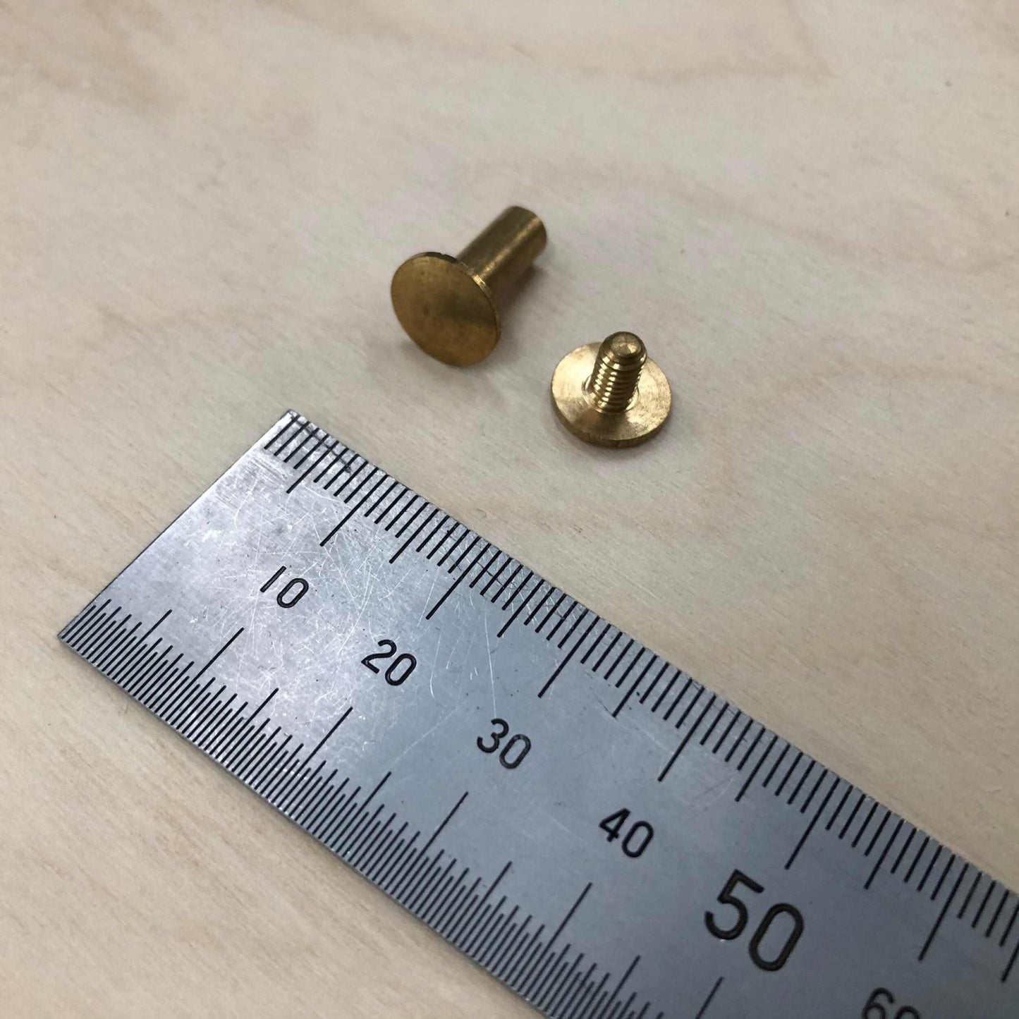 Chicago Screws in solid brass next to a ruler for size reference.