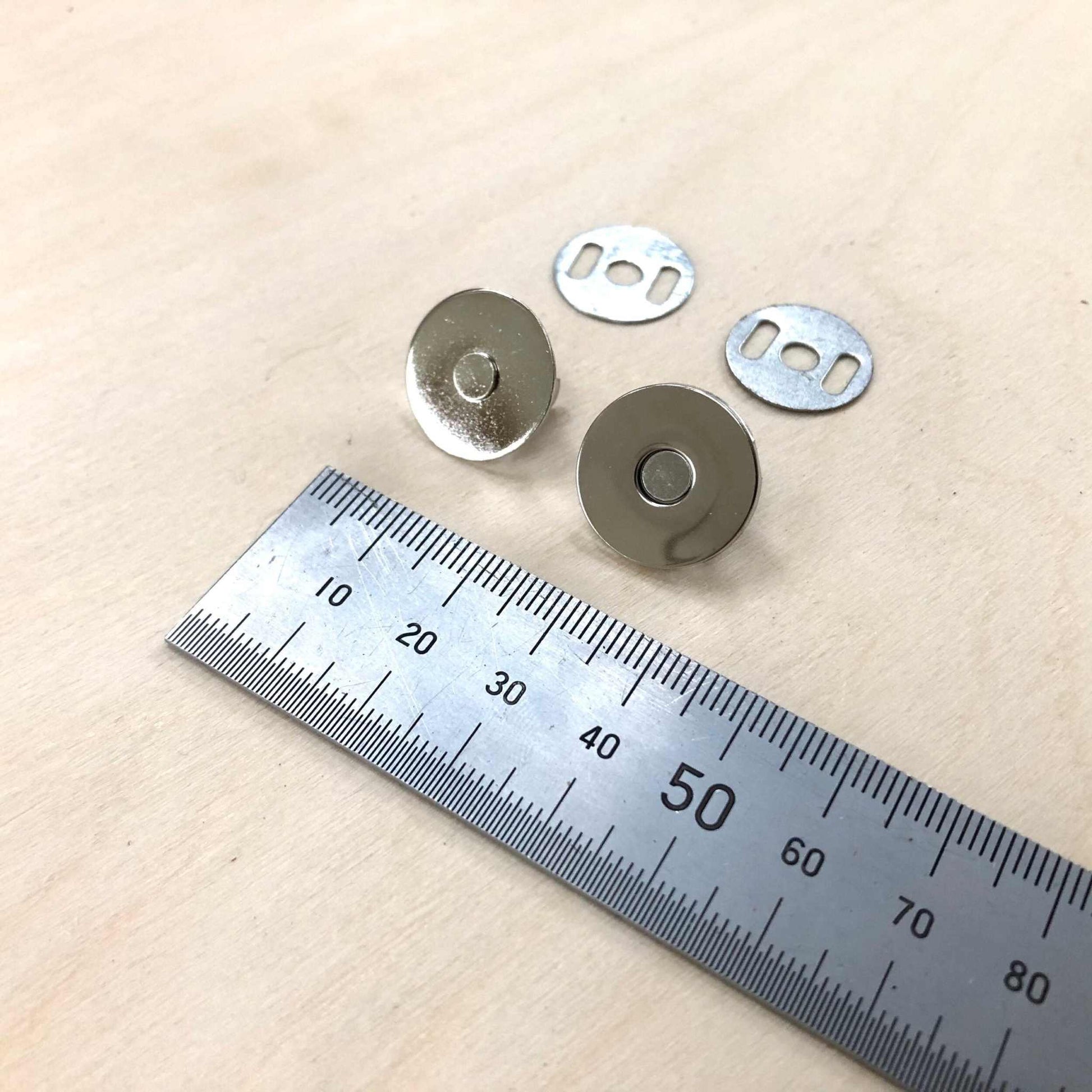 Magnetic Snap Fasteners in gold and silver with back plates next to ruler, 13mm diameter.