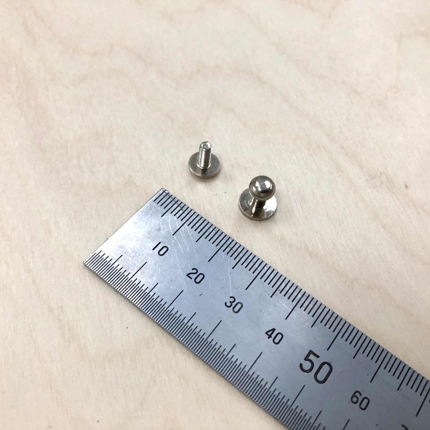 Sam Browne Studs with screws, solid brass or nickel plated, next to a ruler for size reference.