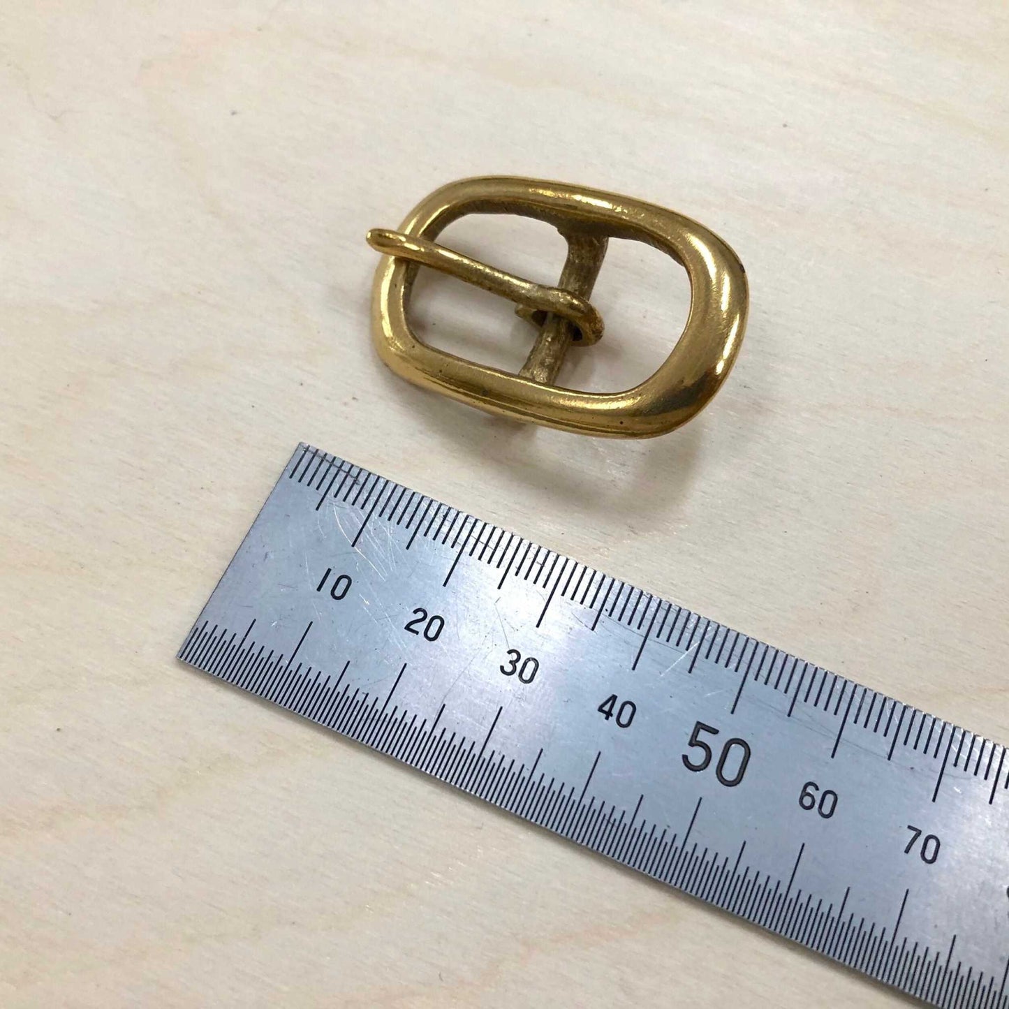 Solid brass belt buckle with double frame and pin, shown with a measuring ruler for scale.