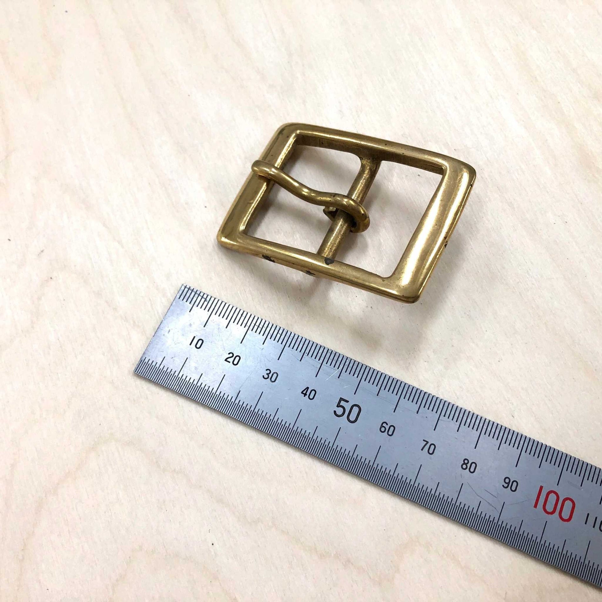 Solid Brass Belt Buckle Double Frame with Pin, Square on wood surface with ruler.