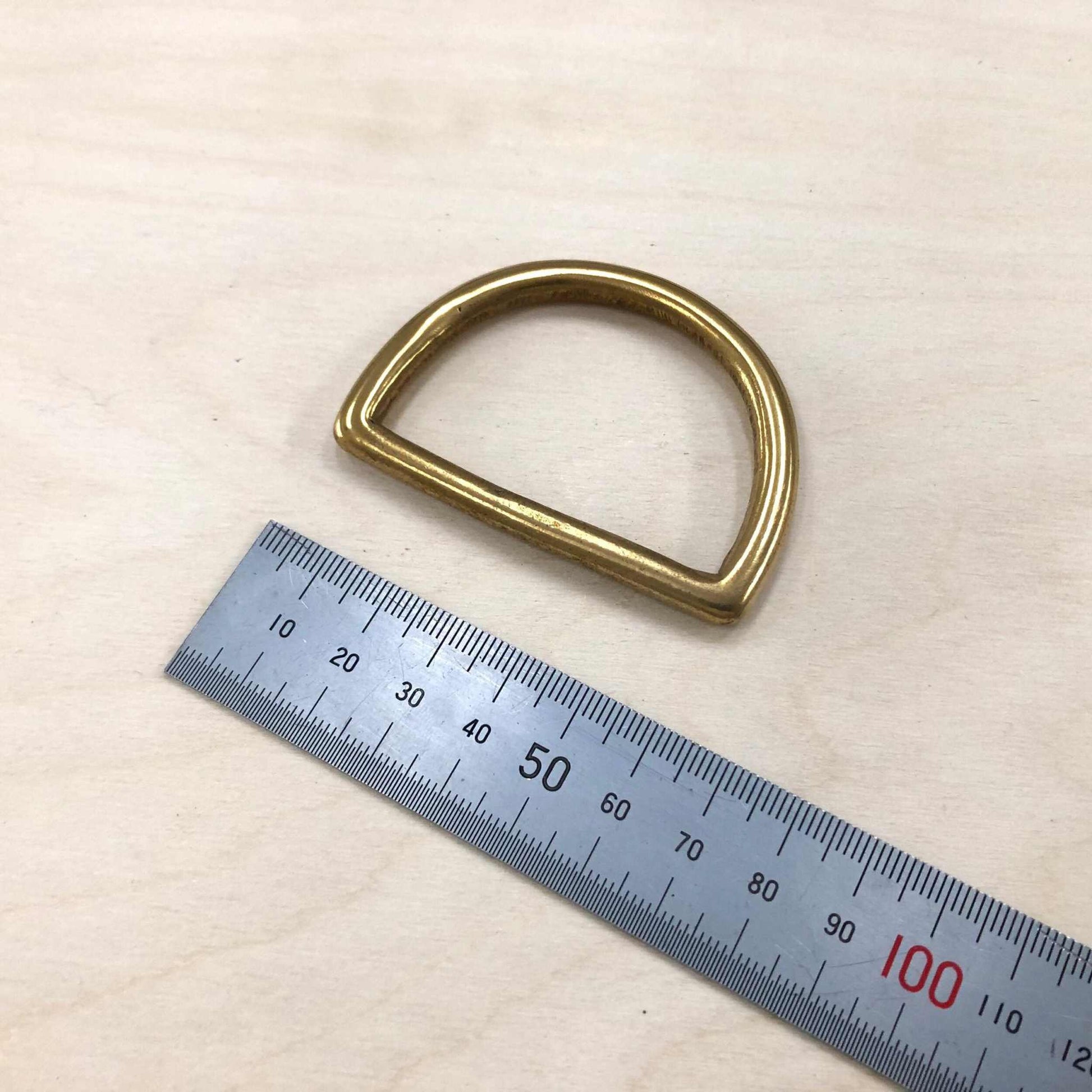 Solid brass D-ring with measurement scale for leather crafting projects.