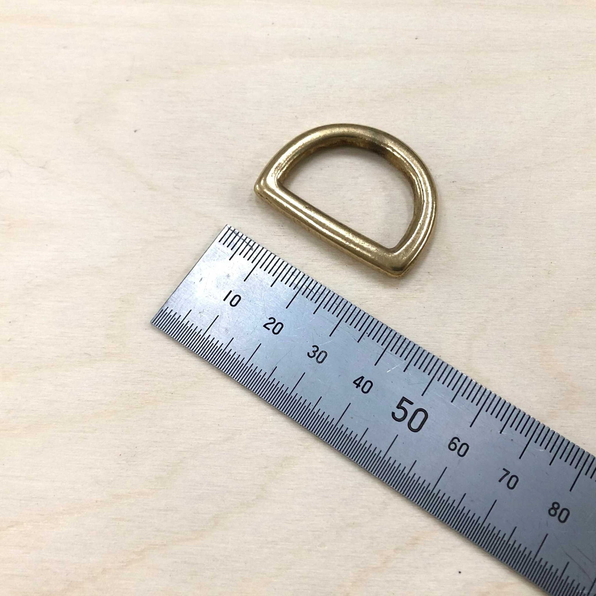 Solid brass D ring with ruler for size reference.